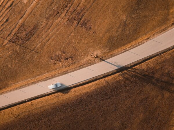 A car speeds along a road through a field.