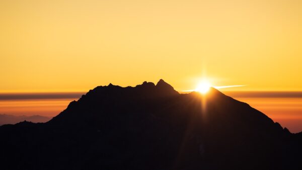 Sunrise peaks over a mountain silhouette.